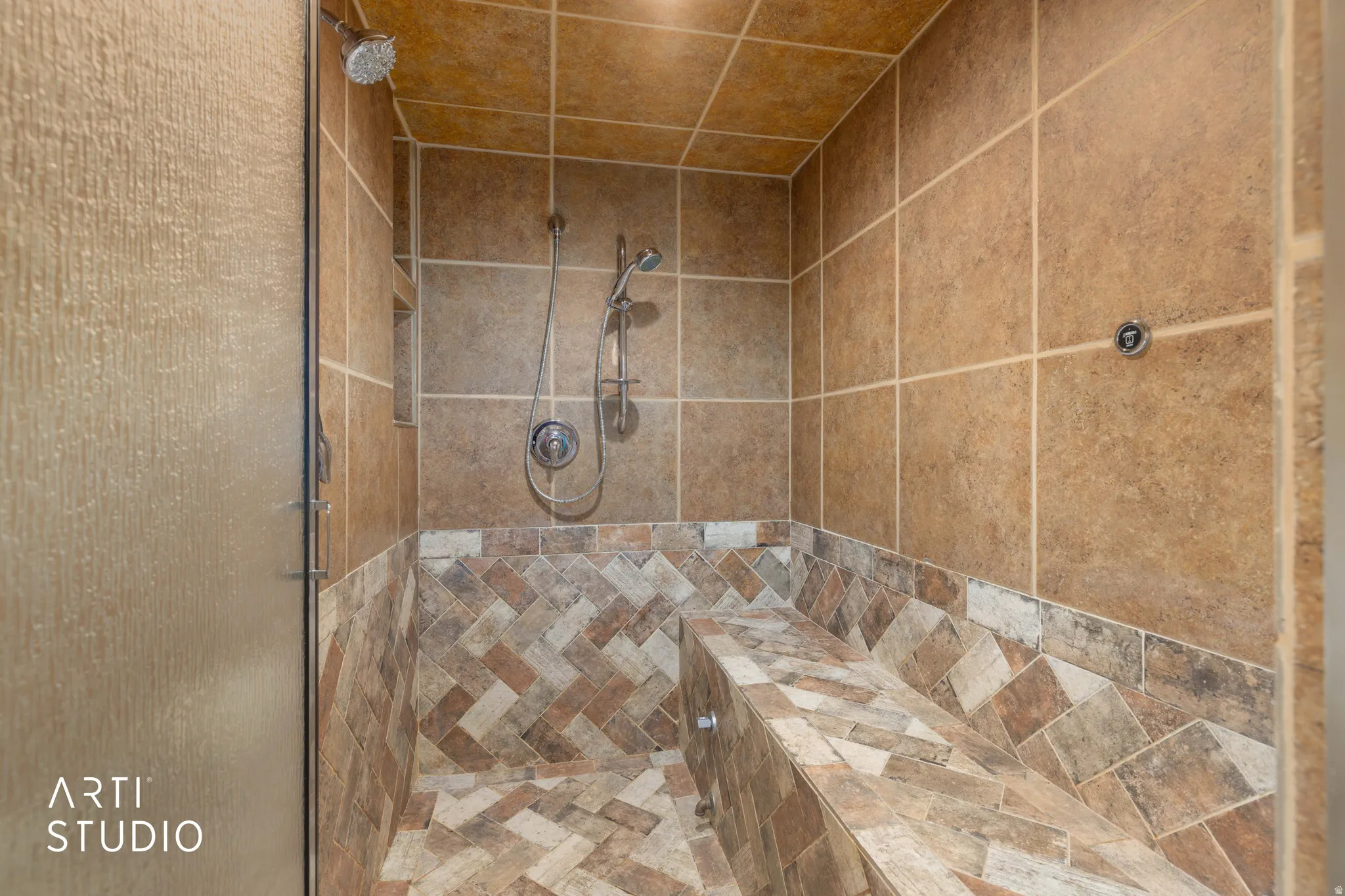 Tiled shower with a mosaic herringbone floor and built-in bench