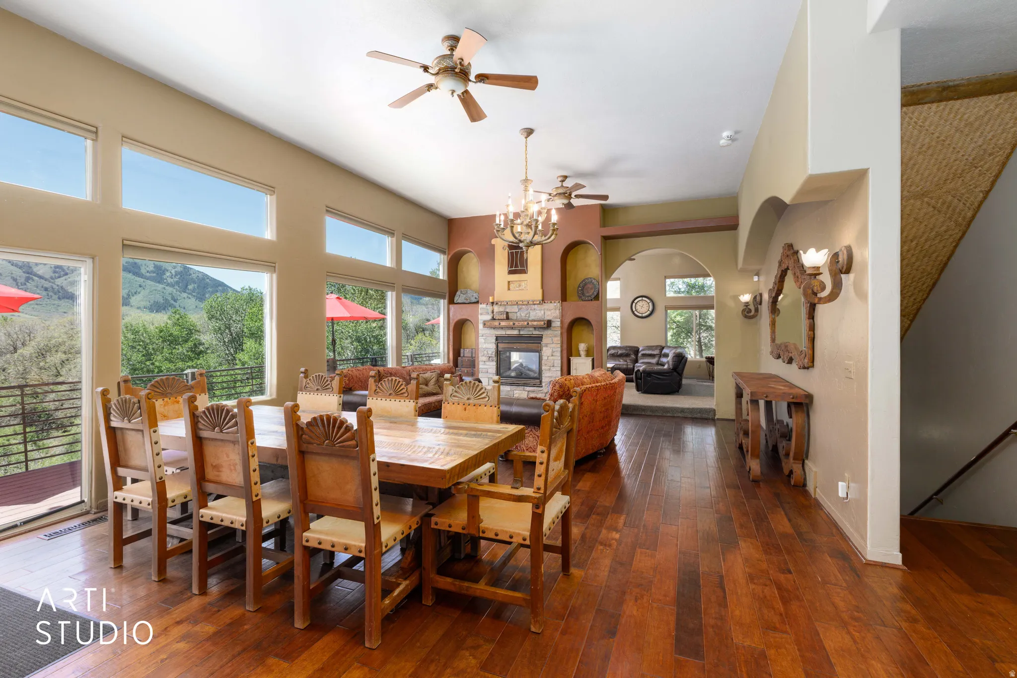 Expansive interior featuring high ceilings, wood-finish flooring, a stone-front fireplace, multiple arched doorways, and large windows