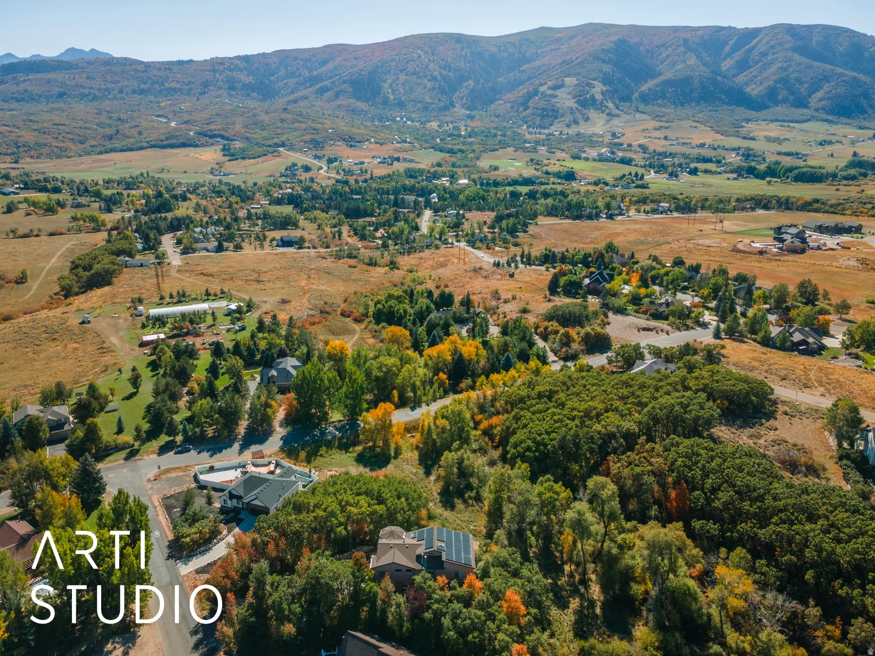 Expansive aerial showcasing a mountainous backdrop, varied topography, and dispersed residential properties