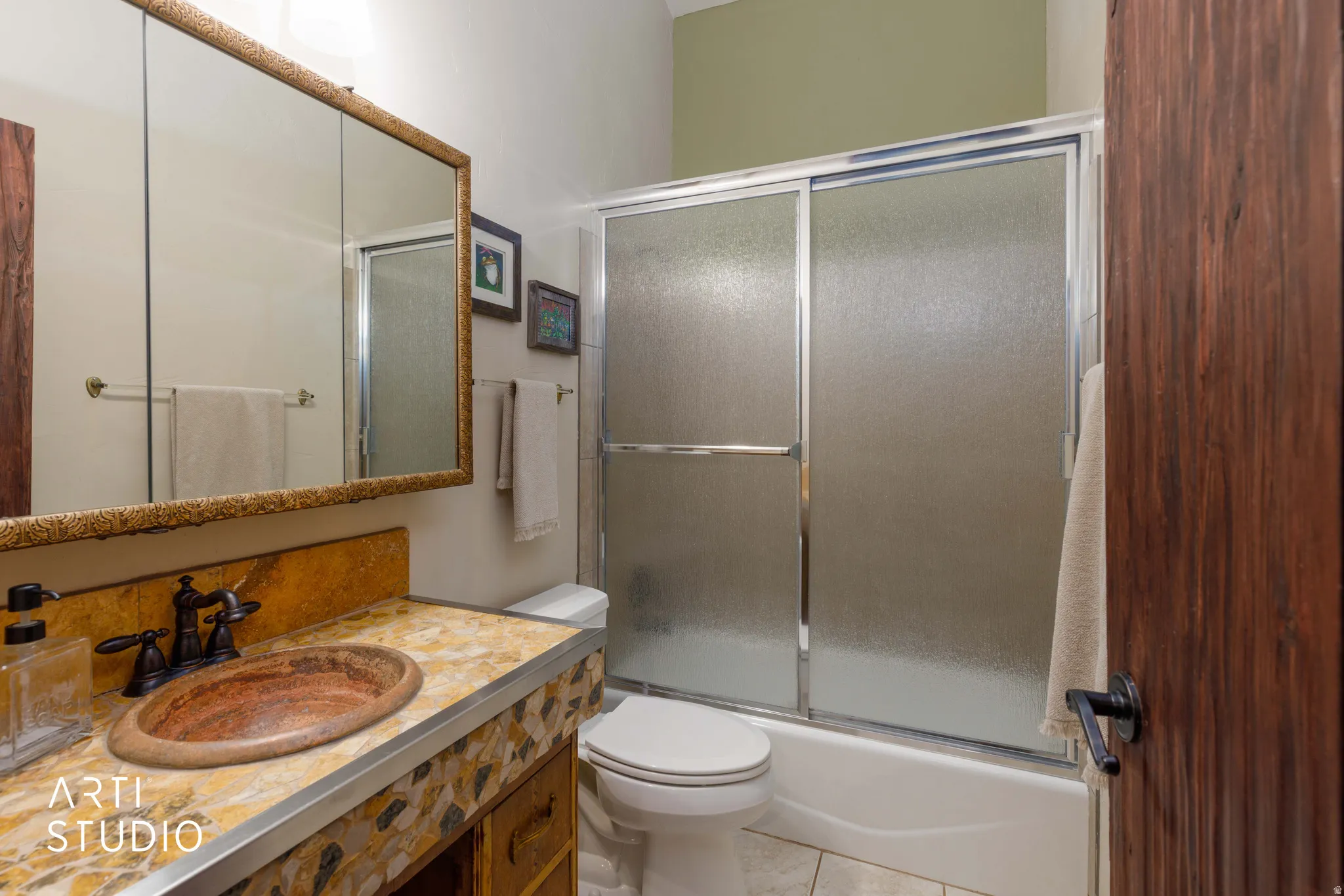 Bathroom featuring a stone vessel sink, patterned stone vanity countertop, bronze-finish faucet, and a large mirrored medicine cabinet