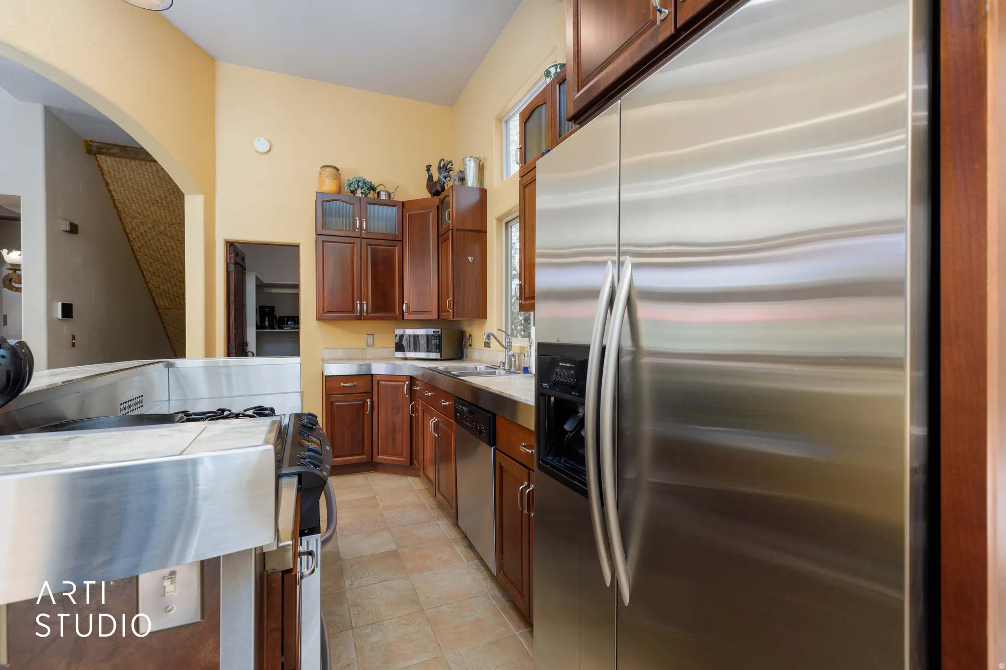 Kitchen featuring stainless steel appliances, wood cabinetry, a built-in microwave, and tile flooring