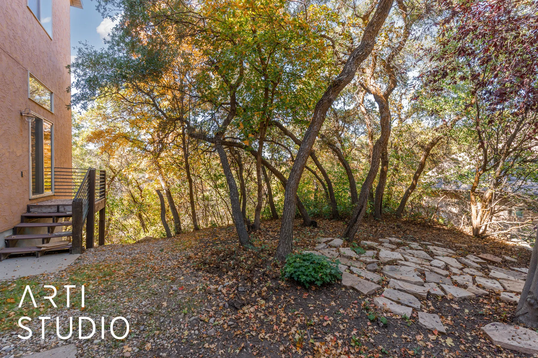 Terraced outdoor space featuring a flagstone patio, mature trees, and natural landscaping