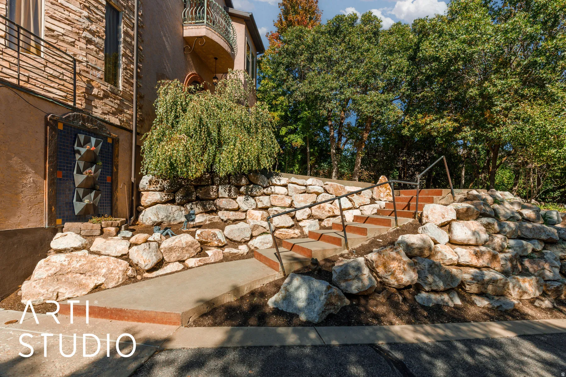 Terraced landscaping featuring a stone retaining wall and concrete steps with black metal railings