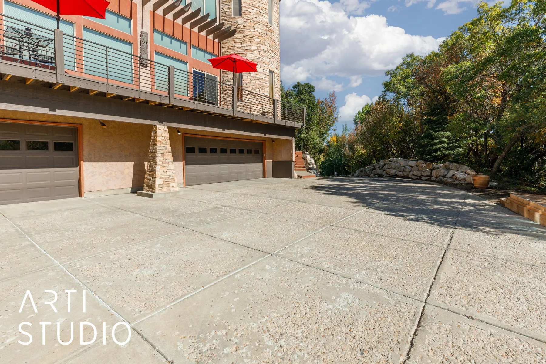 Expansive concrete driveway leading to a multi-car garage with panel doors