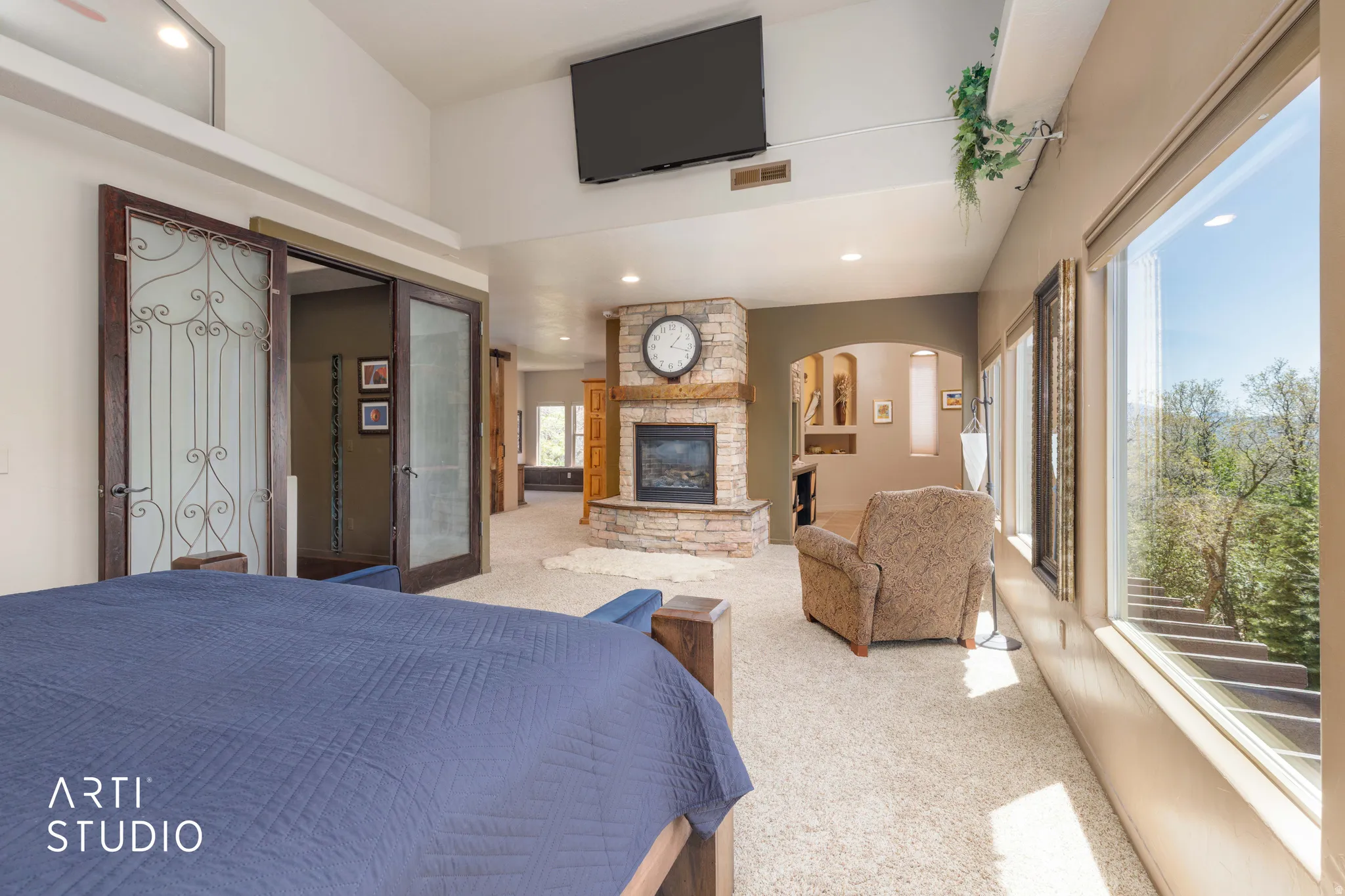 Spacious room featuring vaulted ceilings, a stone fireplace with wood mantel, large windows, and carpet flooring