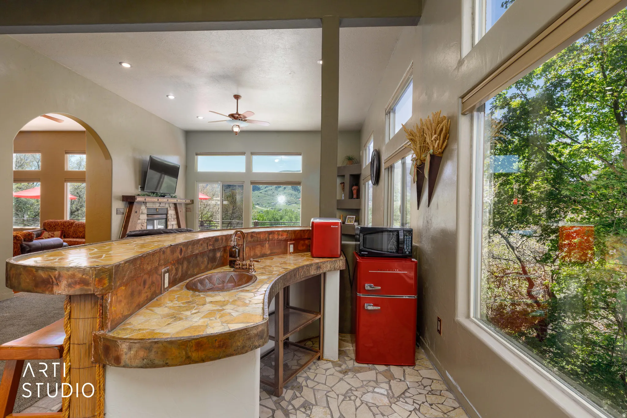 Curved wet bar with a built-in copper sink, wood-finish flooring, recessed lighting, and a window wall