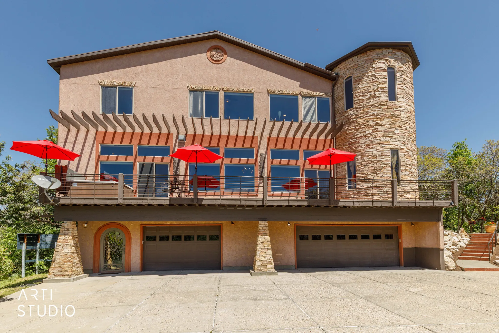 Stucco exterior featuring a stone accent tower and a full-width upper deck with a pergola