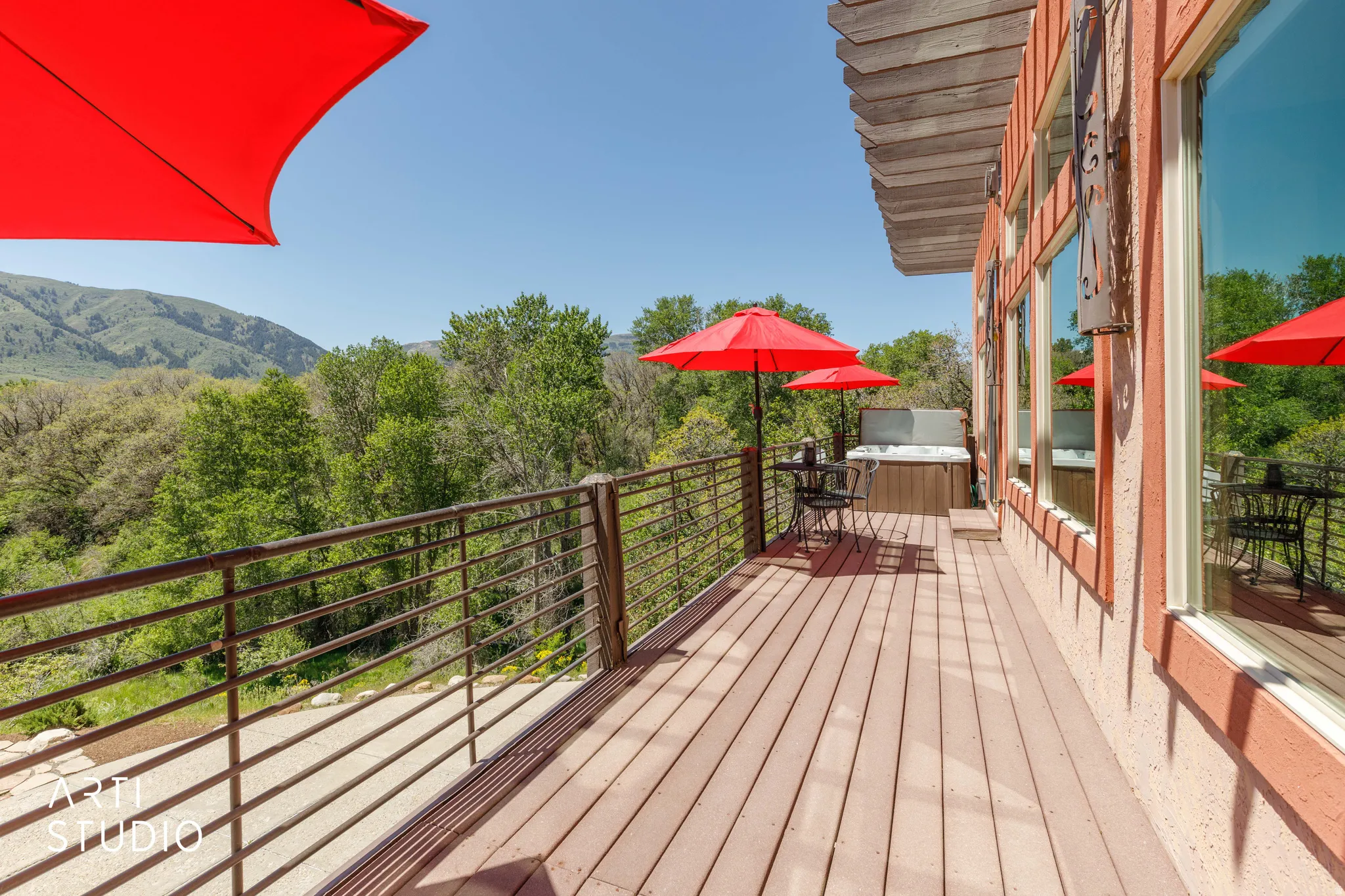 Expansive outdoor deck featuring wood-finish flooring, metal railings, and a built-in spa