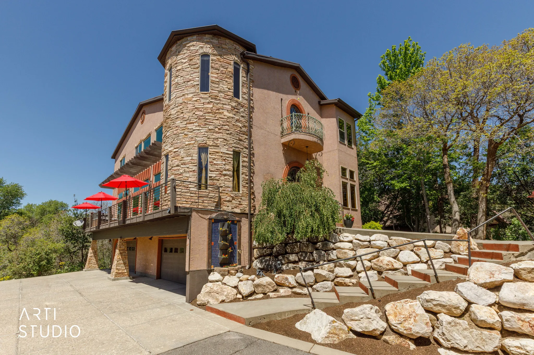Stucco exterior with a stone-clad turret, featuring multiple arched windows and a Juliet balcony