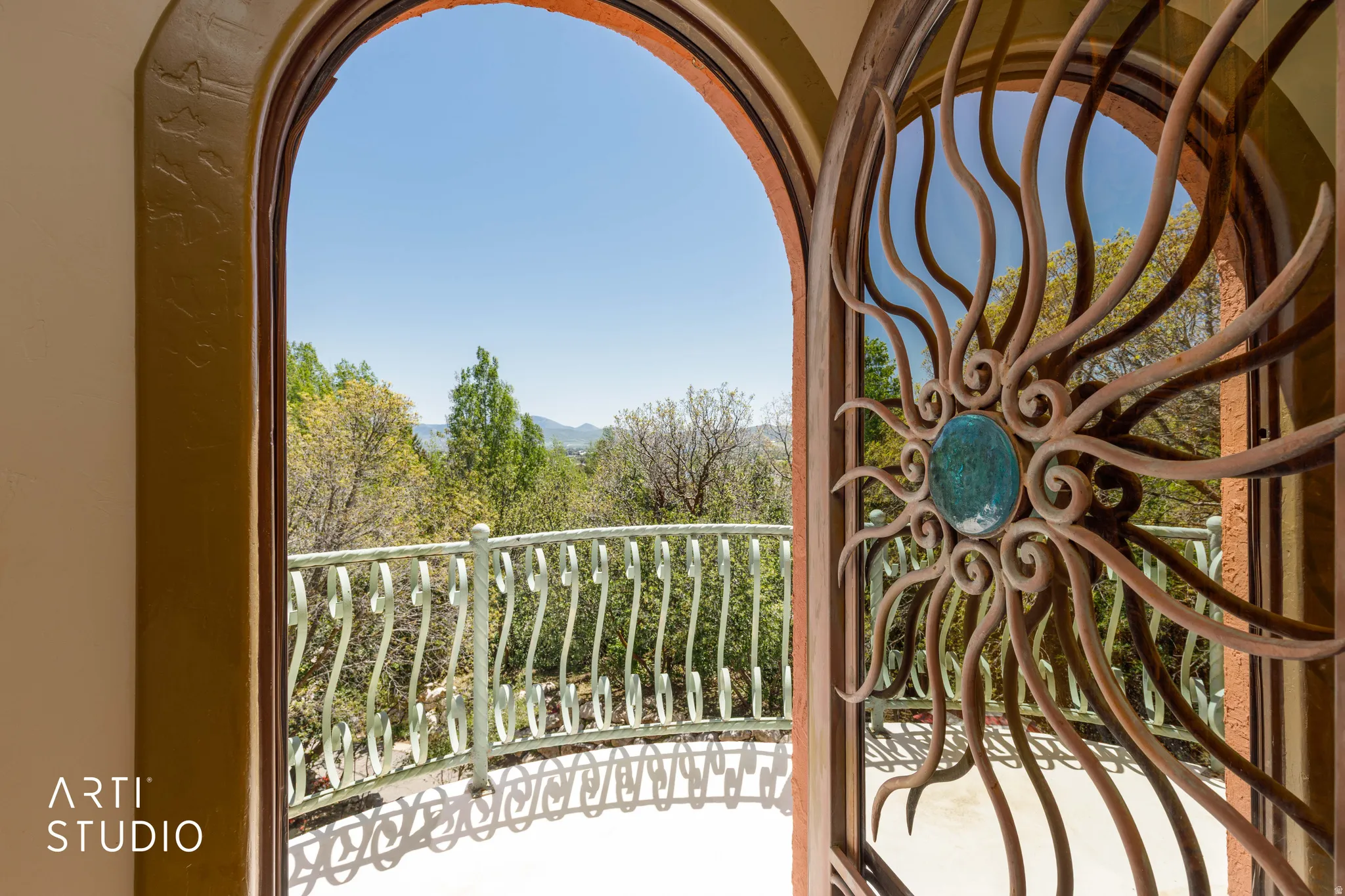 Arched doorway featuring a custom wrought iron gate with a central turquoise accent