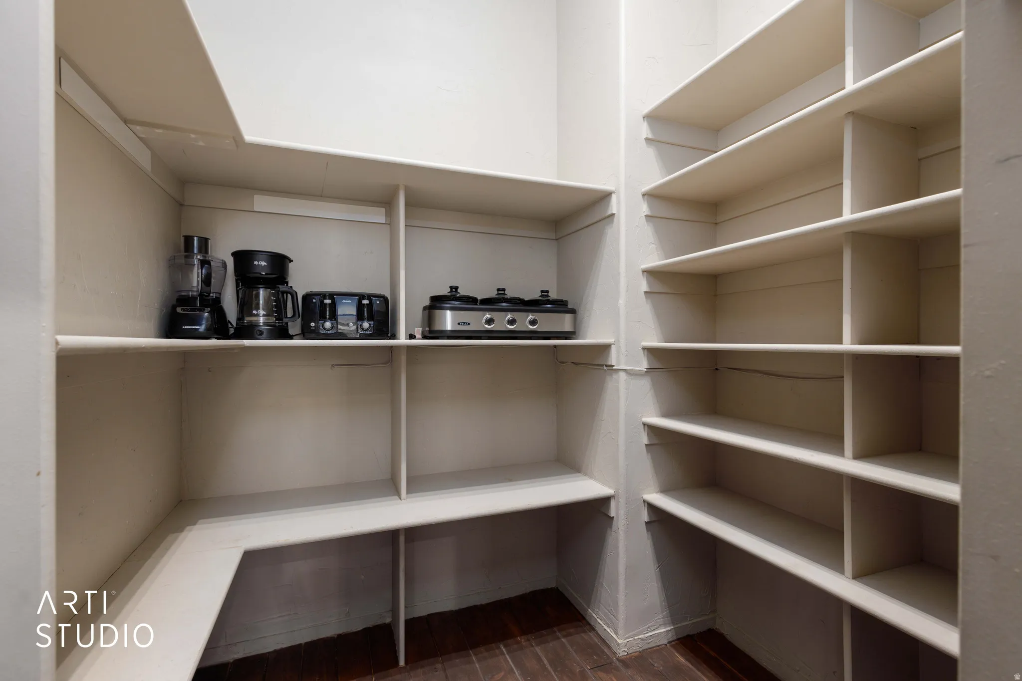Walk-in pantry featuring extensive built-in shelving, durable wood-finish flooring, and ample storage space