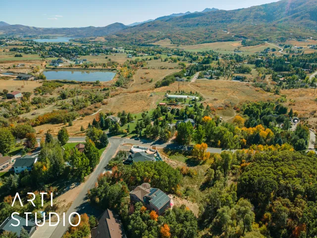 Expansive aerial landscape featuring a lake, surrounding natural terrain, and distant mountains