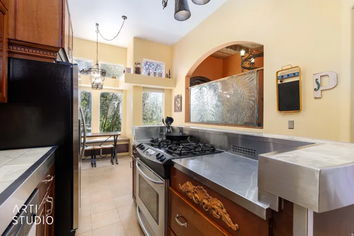 Kitchen featuring stainless steel countertops, a built-in gas range, warm wood cabinetry, and a black refrigerator