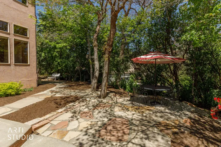 Landscaped outdoor area featuring a flagstone patio, mature trees, mulch ground cover, and a stone pathway