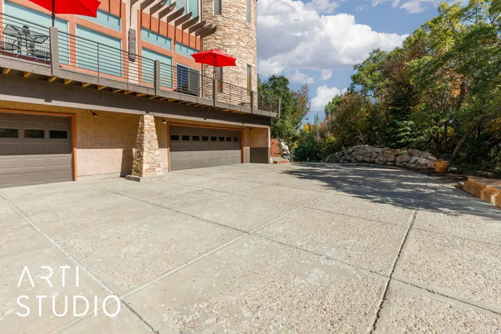 Expansive concrete driveway leading to a multi-car garage with panel doors