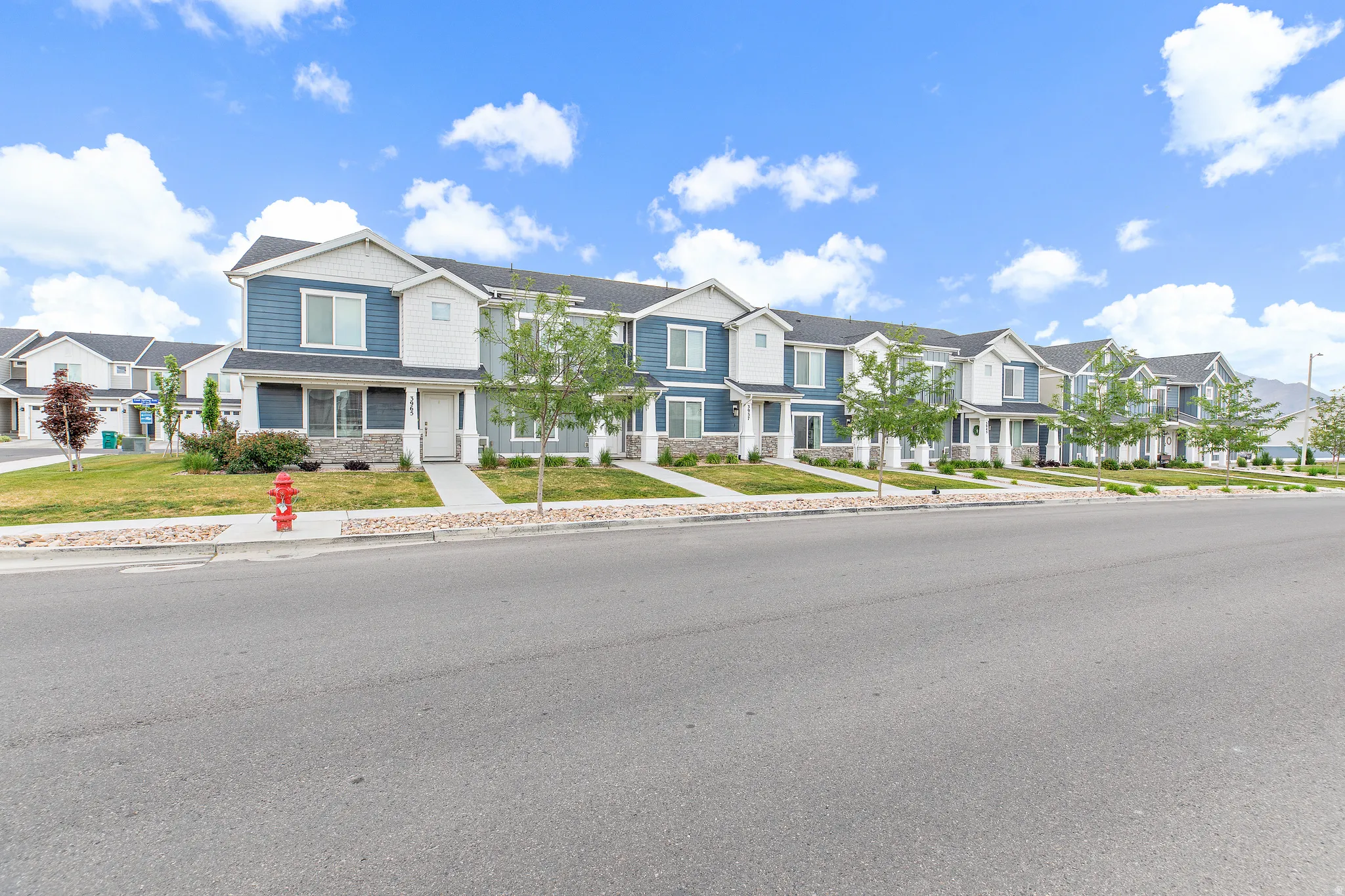 Row of residential townhomes featuring multi-toned siding, stone accents, and covered entryways