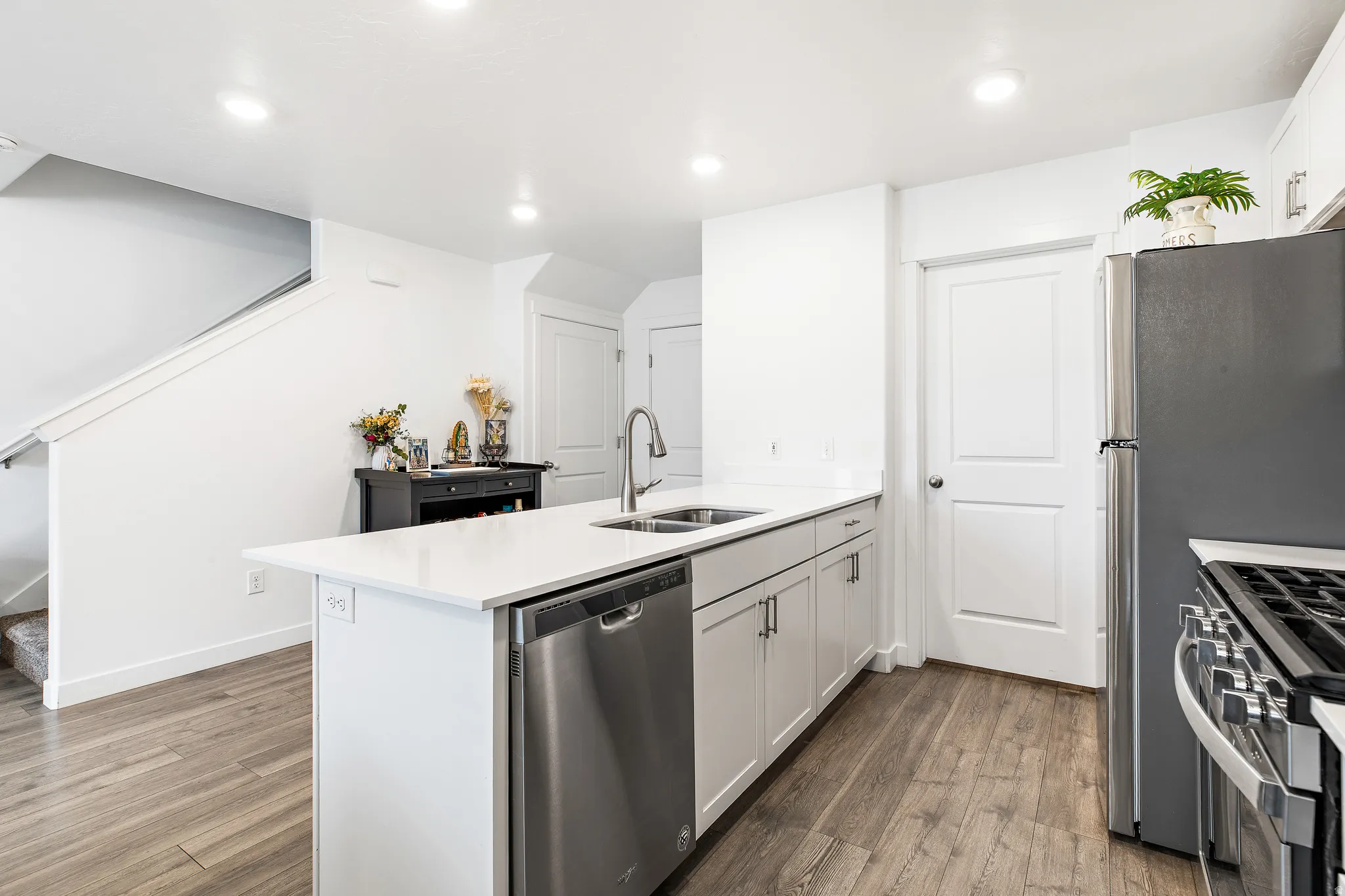 Kitchen island with integrated stainless steel sink and dishwasher, complemented by light cabinetry and white countertops