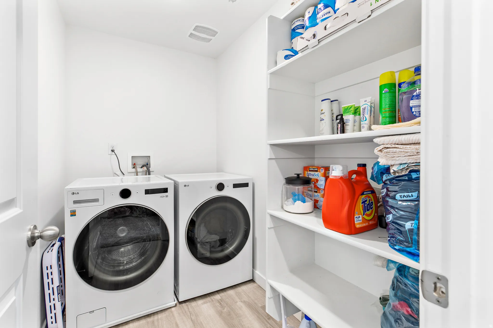 Dedicated laundry area featuring a washer and dryer, built-in shelving, and wood-finish flooring