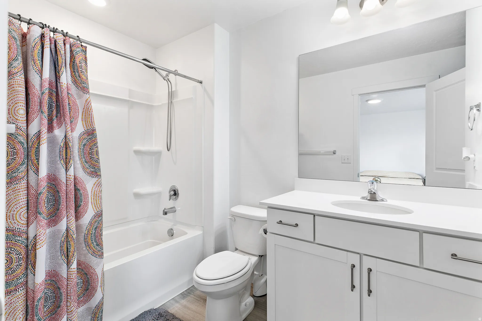 Bright bathroom featuring a white tub and shower combination with chrome fixtures, a white vanity with a single basin sink, and a large wall-mounted mirror