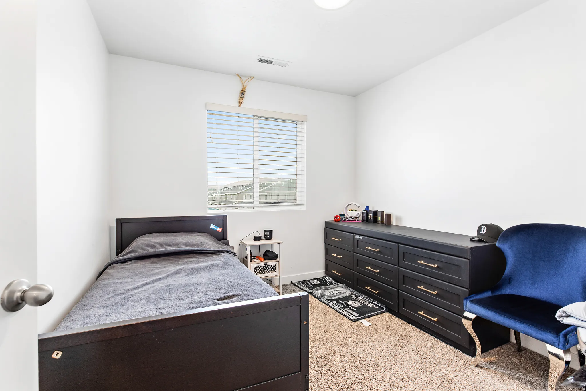 Bright room featuring a window with horizontal blinds, neutral carpet flooring, and white painted walls