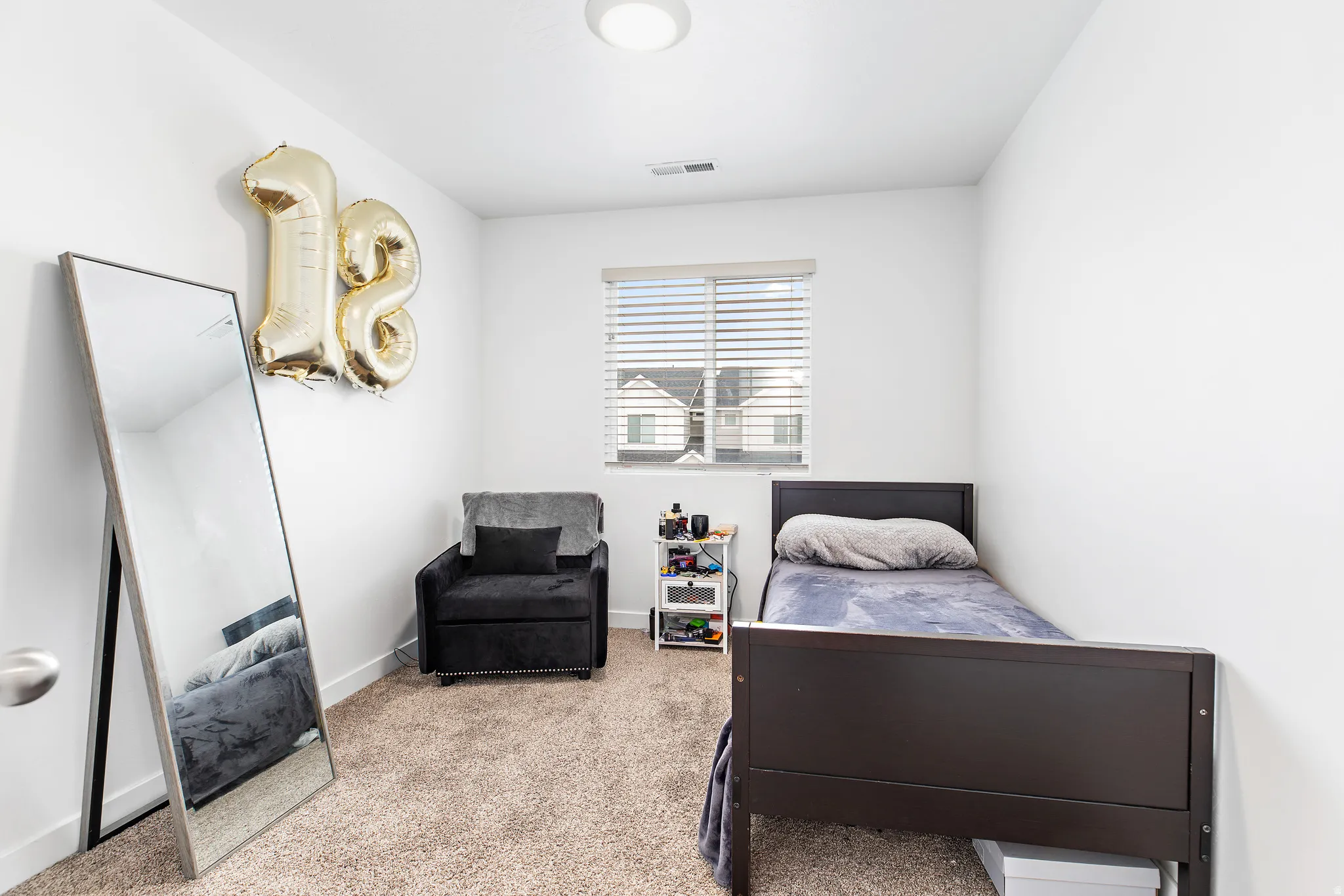 Carpeted room featuring a single window with horizontal blinds, providing natural light
