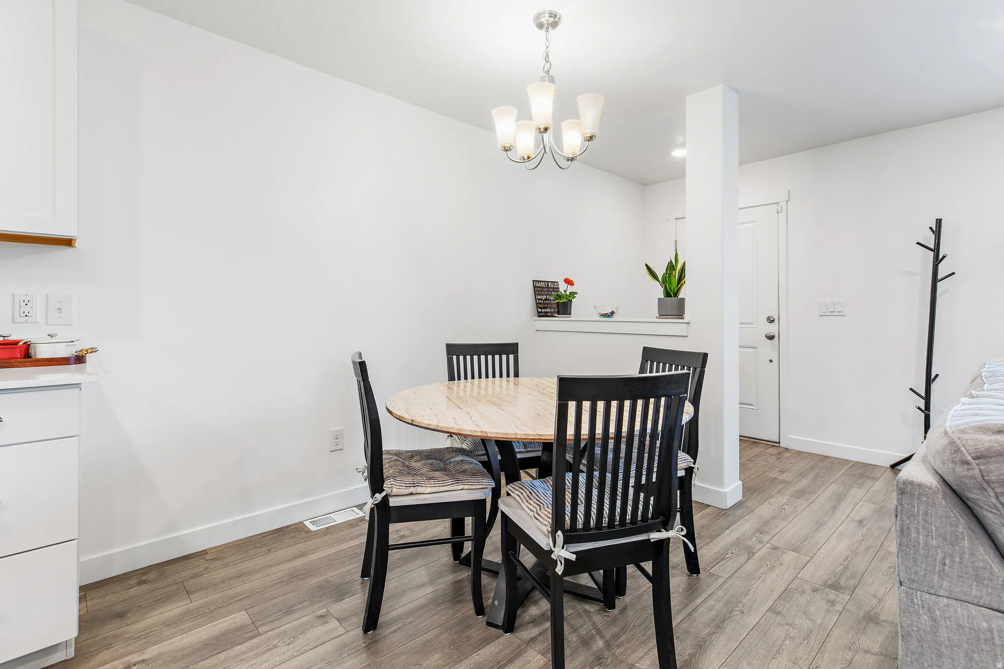 Dining area featuring wood-finish flooring, a contemporary chandelier, and a built-in half-wall with a ledge