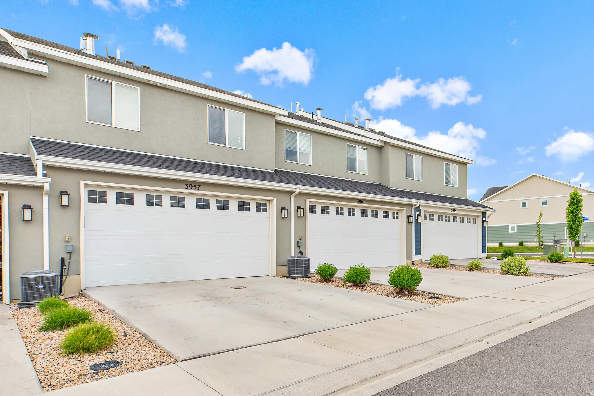 Modern townhome exterior featuring stucco siding and multiple garage bays