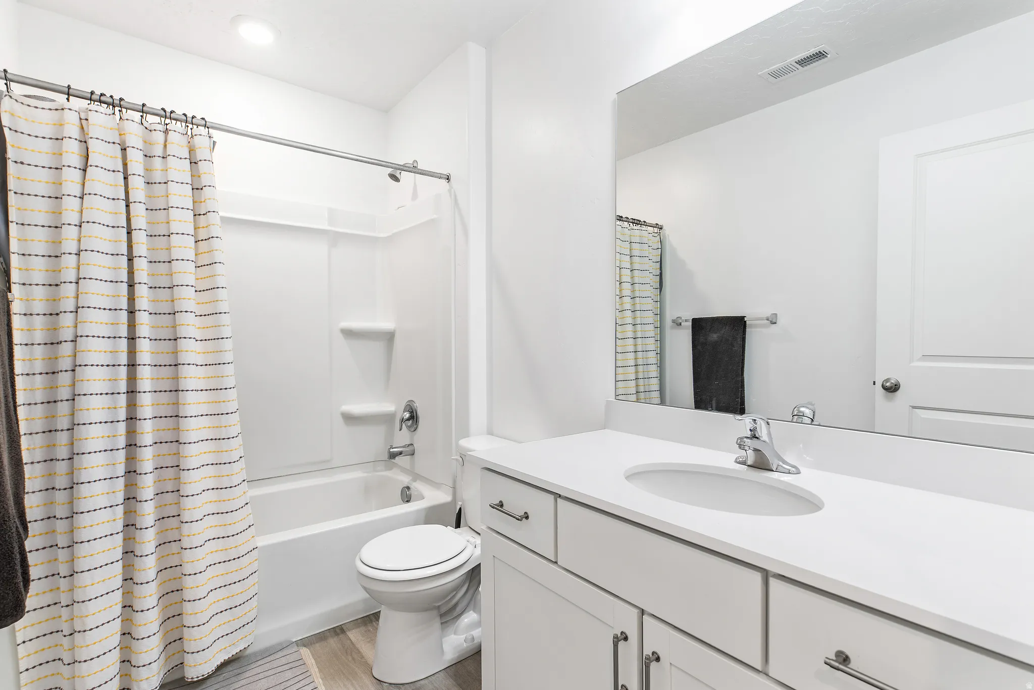 Bathroom featuring a white vanity with an integrated sink, polished chrome faucet, and a large wall-mounted mirror