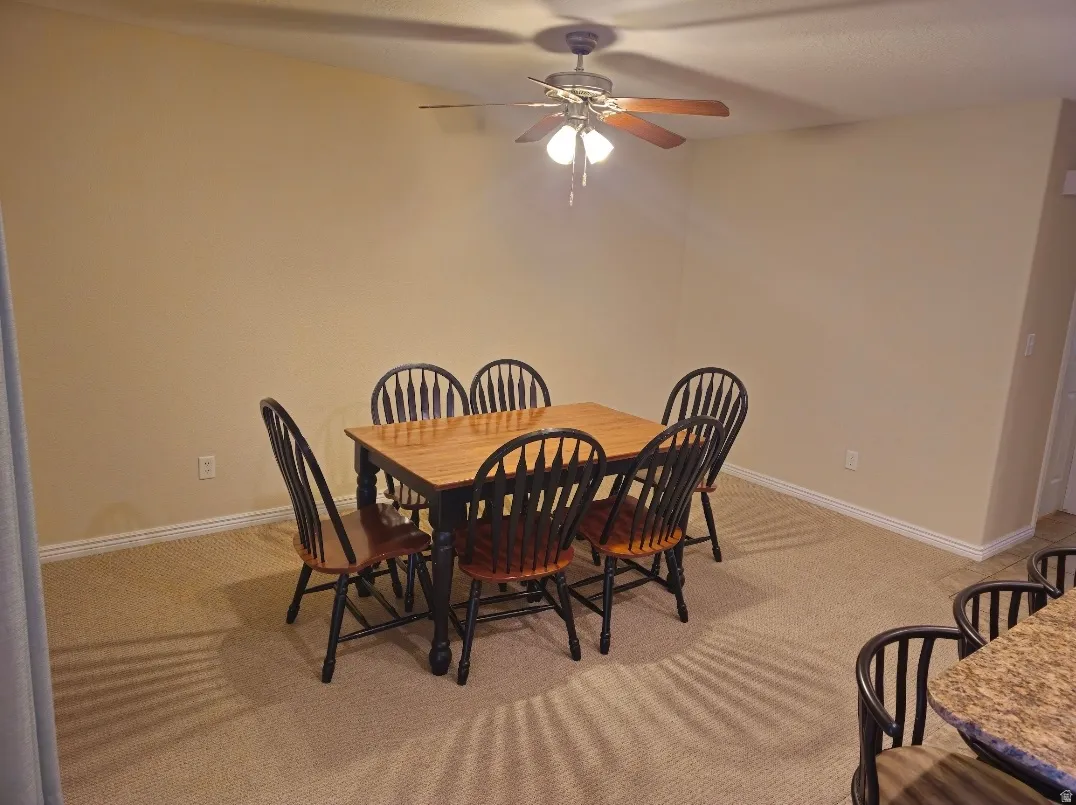 Dining area featuring neutral carpeting, a ceiling fan with integrated lighting, and light-toned walls