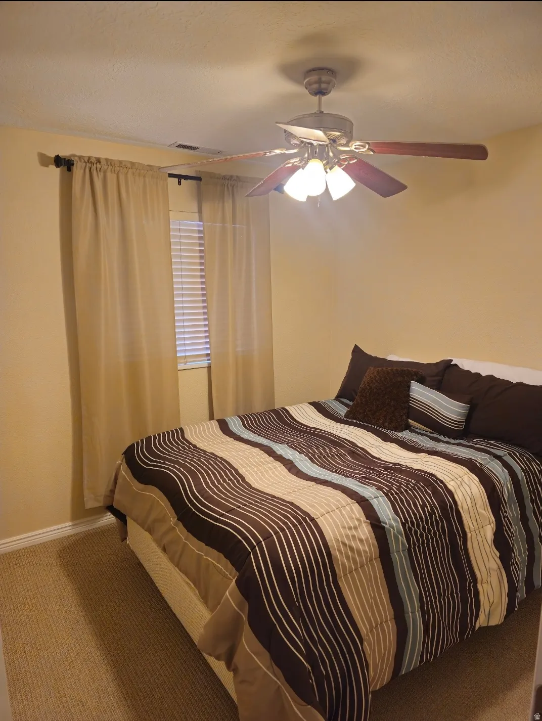 Carpeted room featuring a ceiling fan with integrated lighting, window with blinds, and neutral wall paint