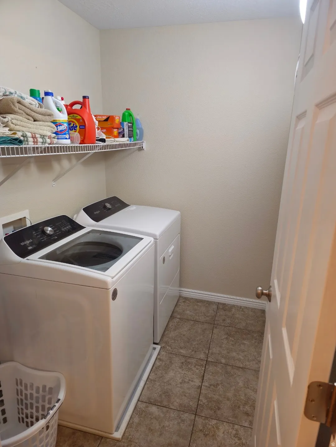 Dedicated utility space featuring tiled flooring, a wire shelf, and baseboard molding