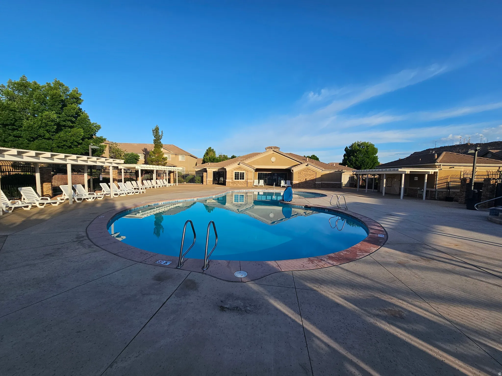 Circular inground pool featuring metal handrails and a concrete surround