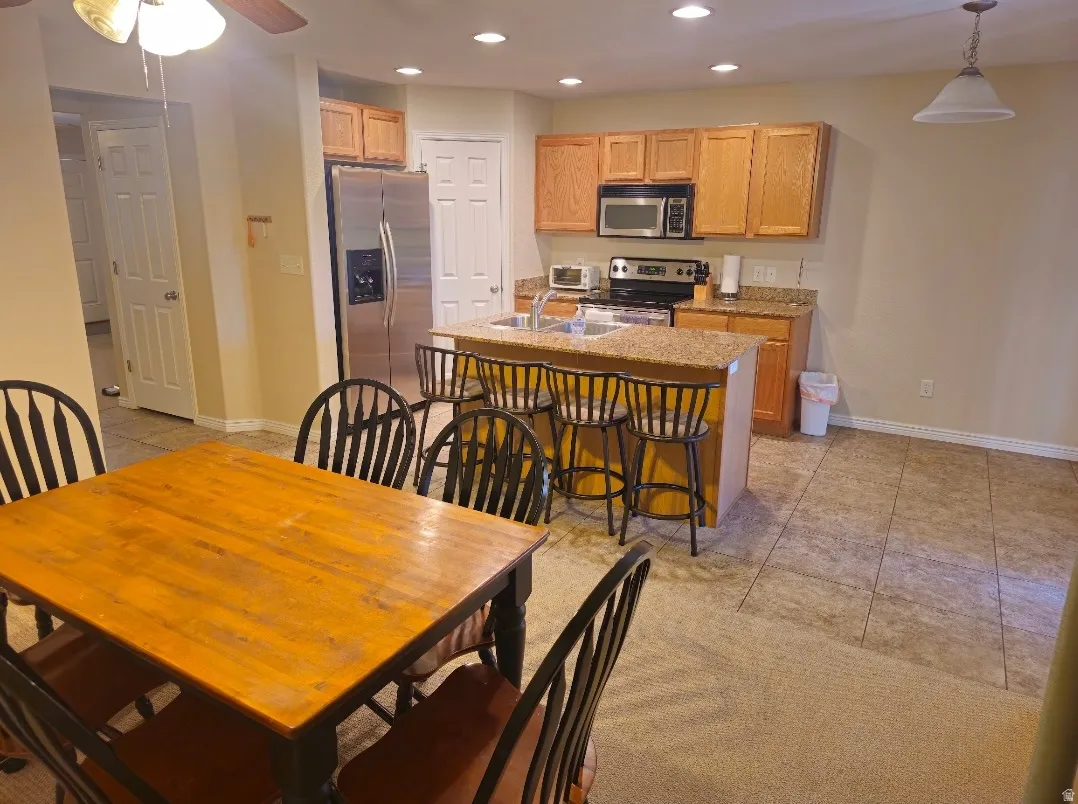 Kitchen features a granite-topped island with seating, natural wood cabinetry, and stainless steel appliances