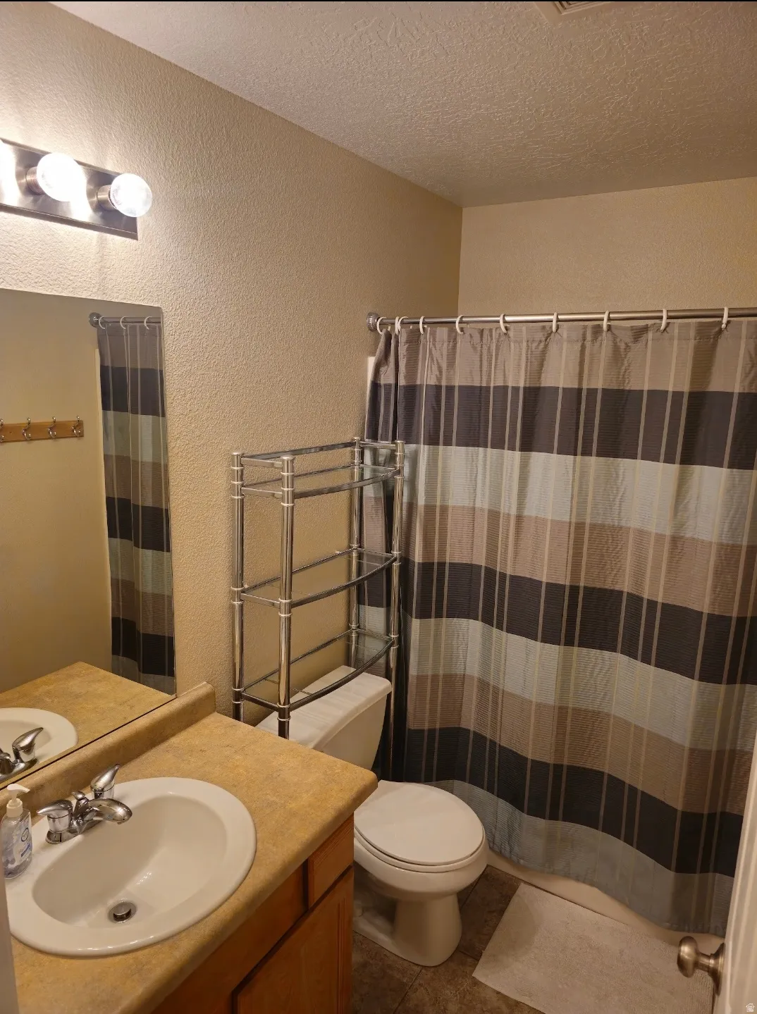 Bathroom featuring a single vanity with a laminate countertop, undermount sink, and chrome faucet