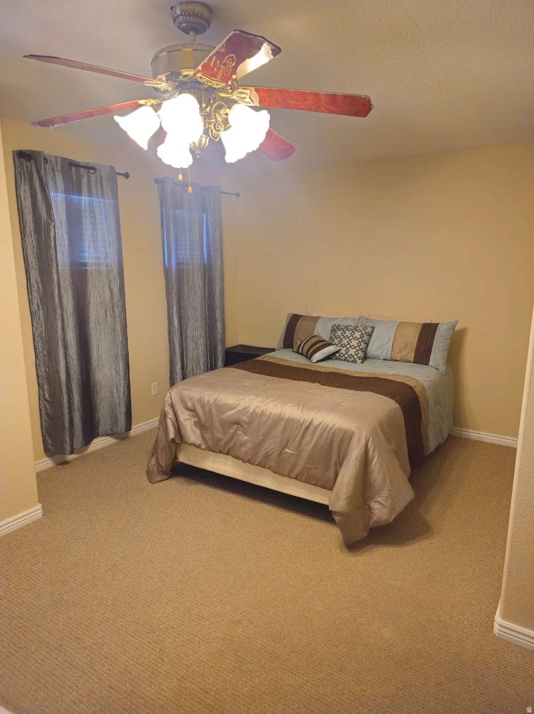 Carpeted room featuring a ceiling fan with integrated lighting, two windows with blinds, and neutral wall tones