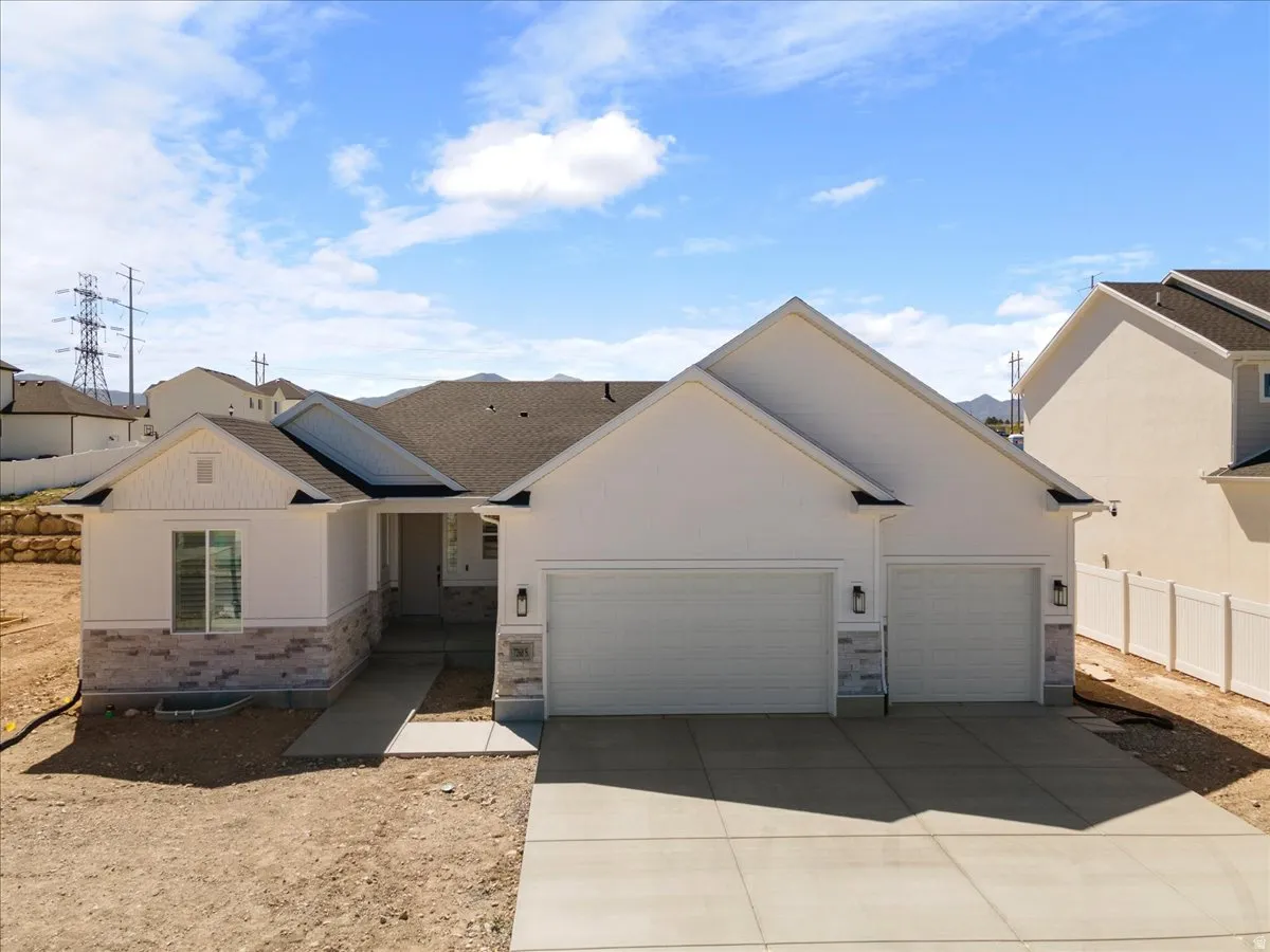 Contemporary exterior featuring white stucco, stacked stone accents, and a dual garage