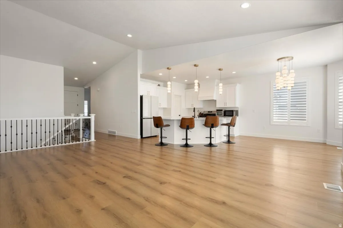Open-concept living space featuring wood-finish flooring, vaulted ceilings, and recessed lighting