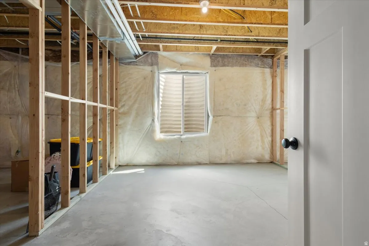 Unfinished basement space with exposed wood framing, concrete flooring, and ceiling joists
