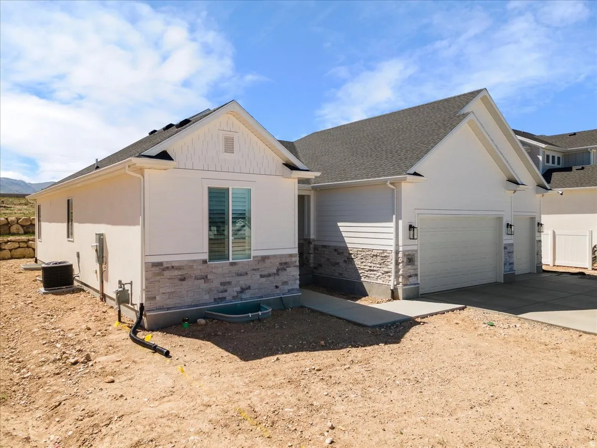 Modern exterior featuring white siding, a contrasting stone veneer accent, and a dark shingled roof