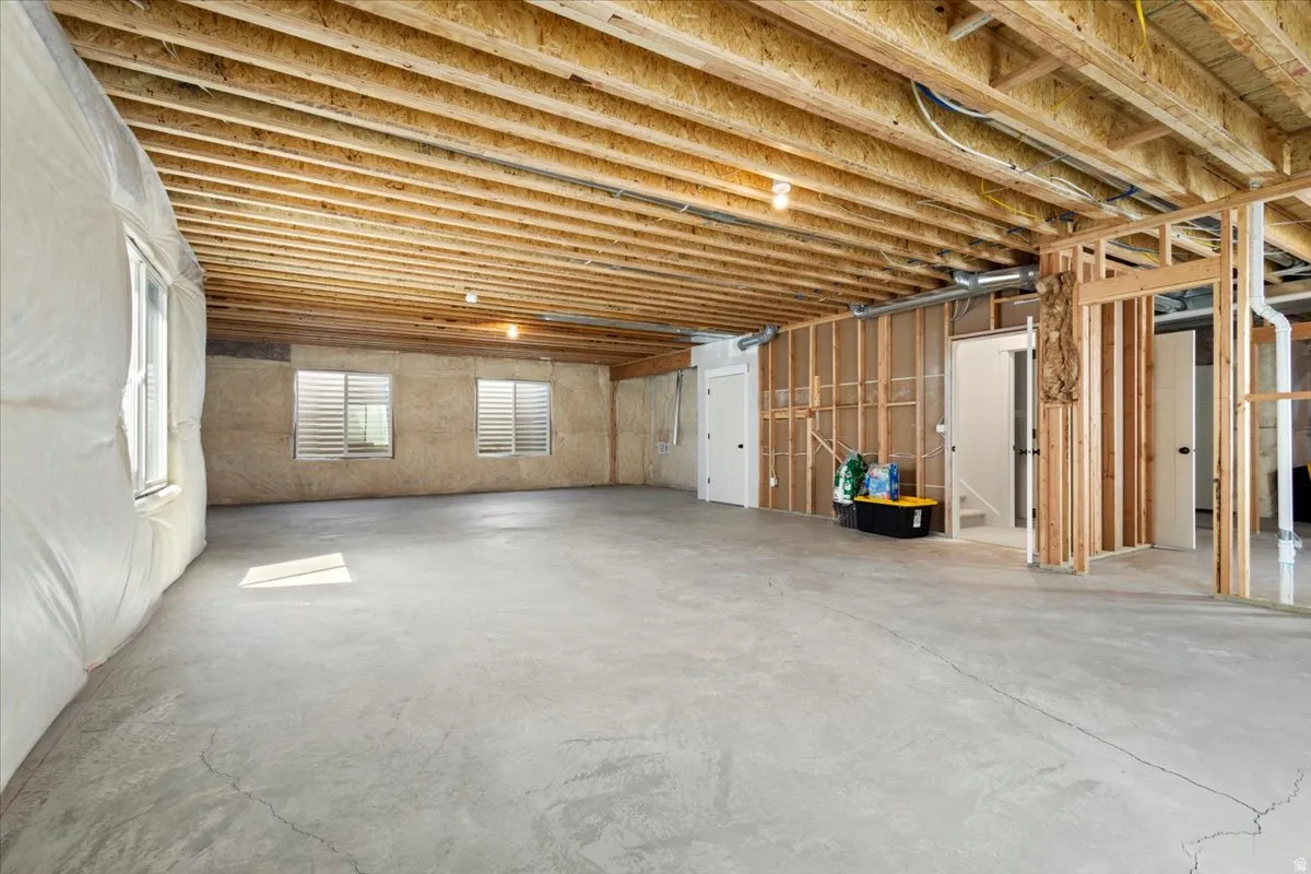 Unfinished lower level featuring exposed wood joists, concrete flooring, and multiple framed interior walls