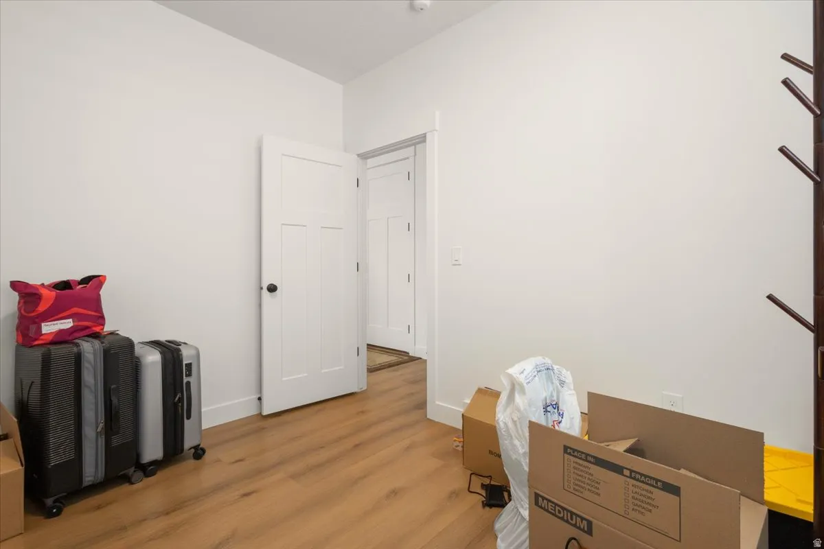 Spacious room featuring wood-finish flooring and crisp white walls