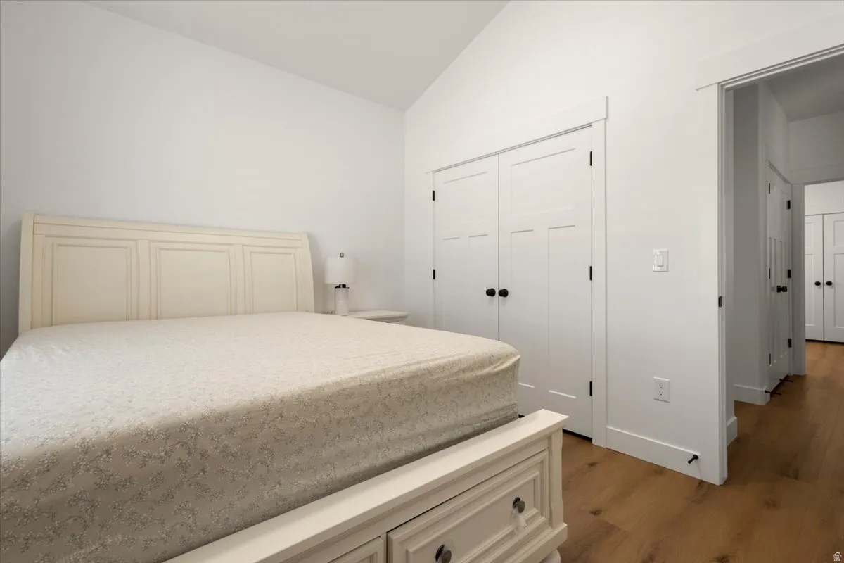 Bedroom featuring a vaulted ceiling and wood-finish flooring