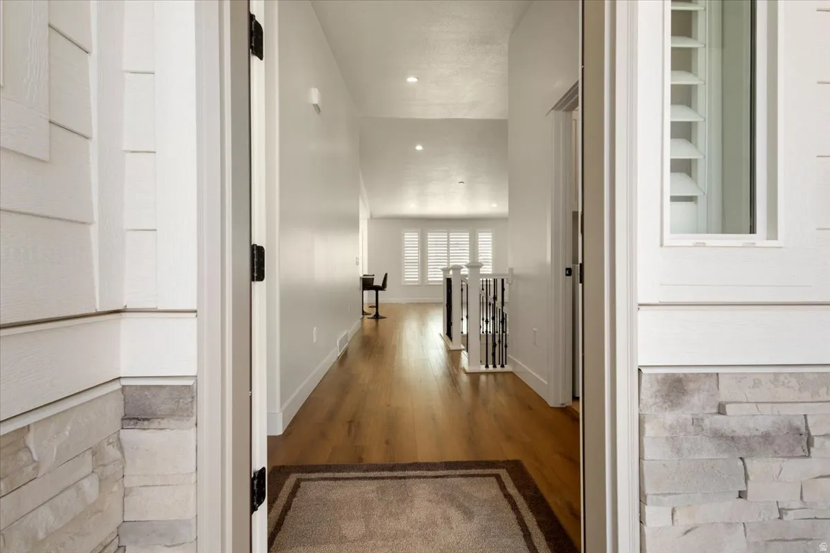 Entryway featuring light wood-finish flooring, recessed lighting, and a white spindle staircase railing