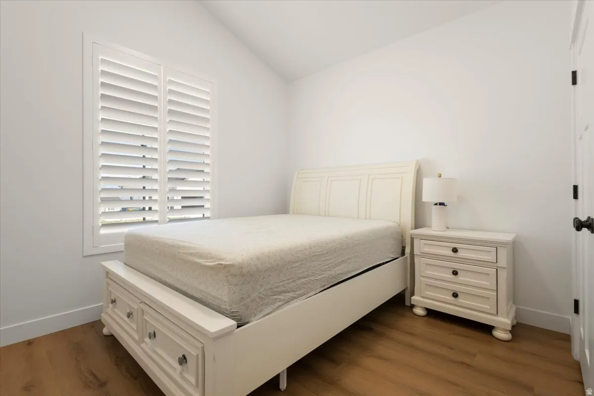 Vaulted ceiling with bright white walls and wood-finish flooring