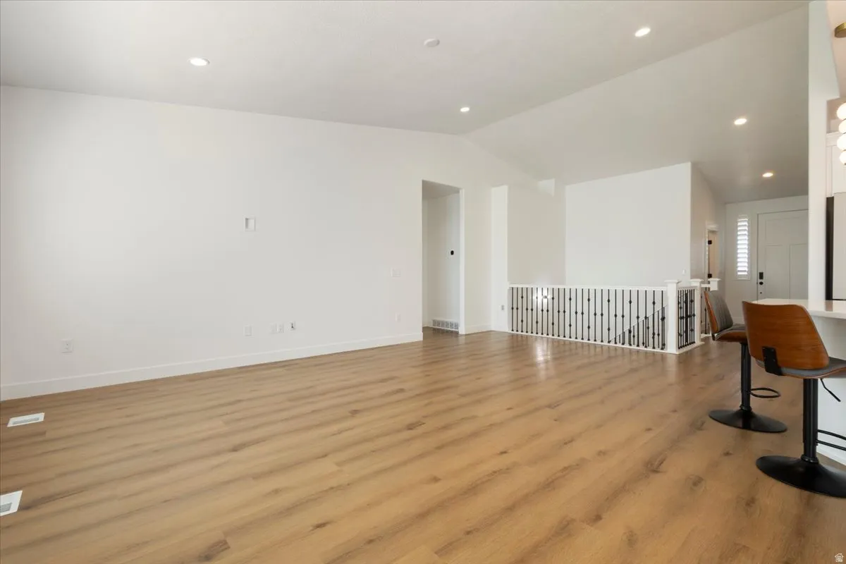 Spacious living area featuring wood-finish flooring, recessed lighting, and a white interior palette