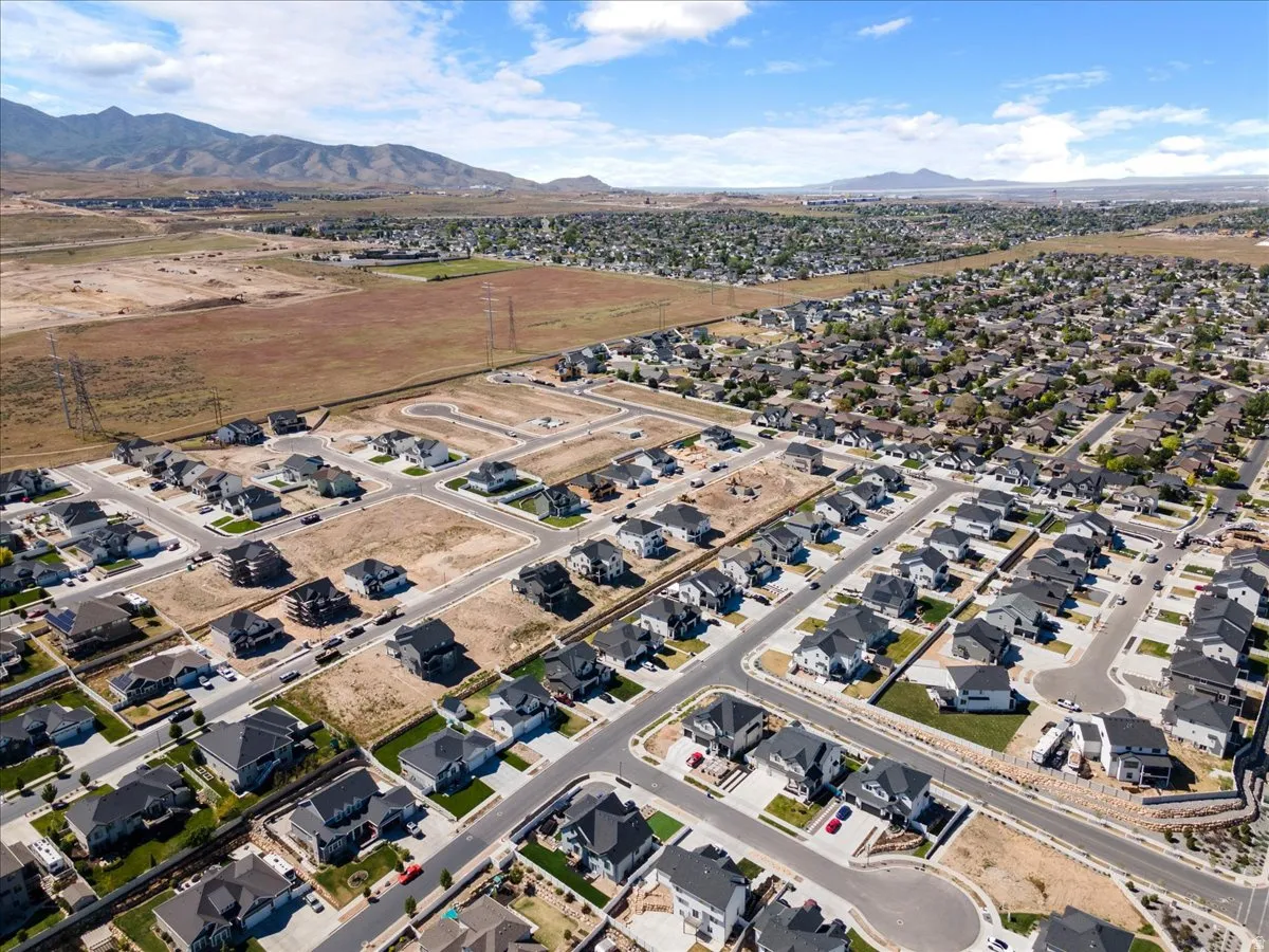 Expansive aerial view showcasing a developing residential community with numerous homes featuring dark roofs