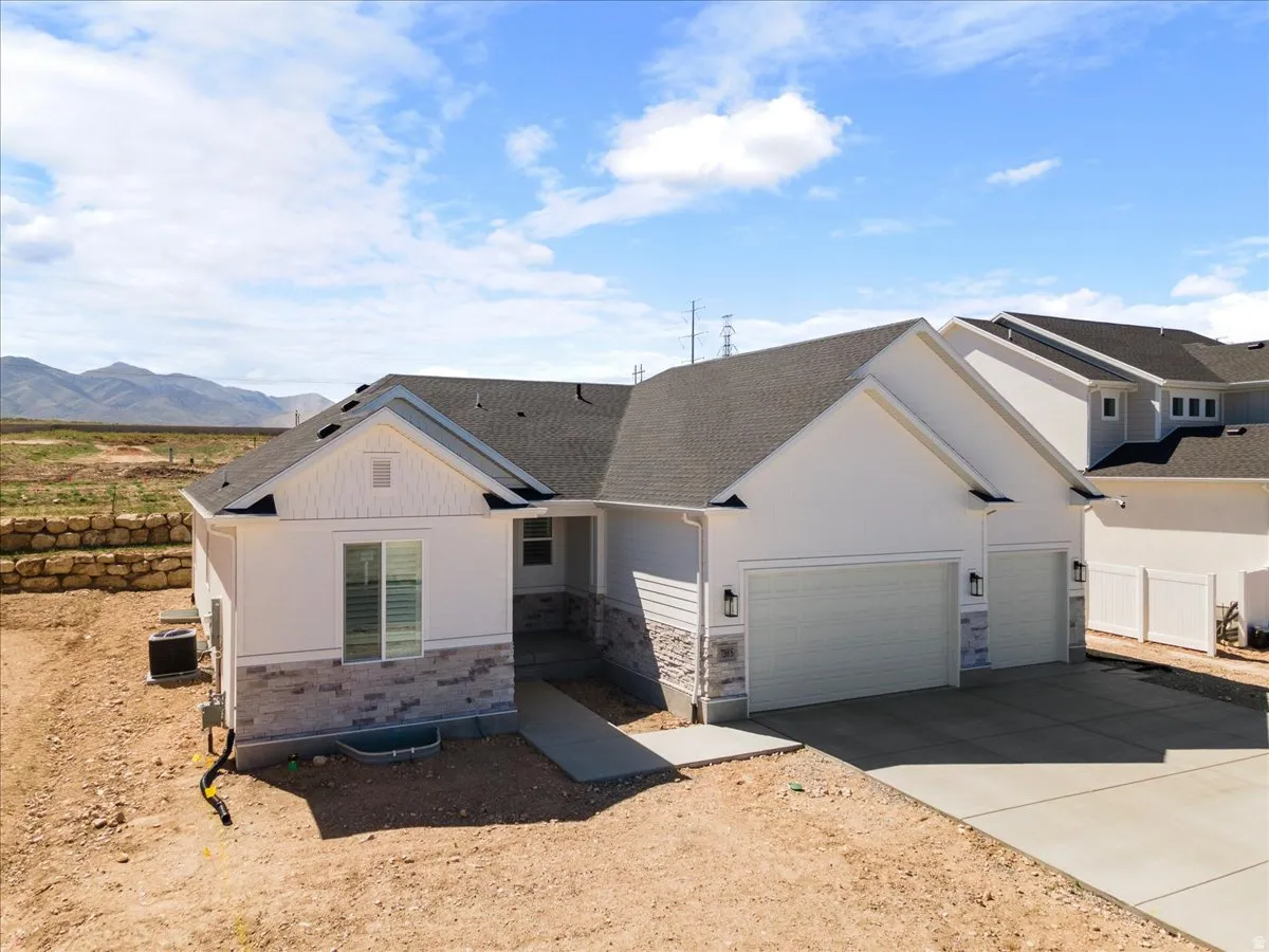 Contemporary single-story residence featuring a two-car garage, white siding, and a stone facade