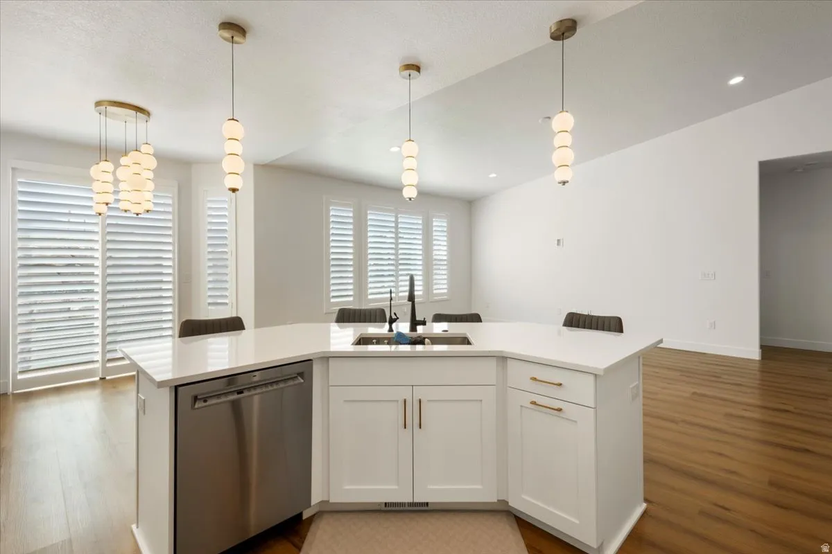 Kitchen island featuring a white countertop, integrated sink with a matte black faucet, and white cabinetry with brass hardware