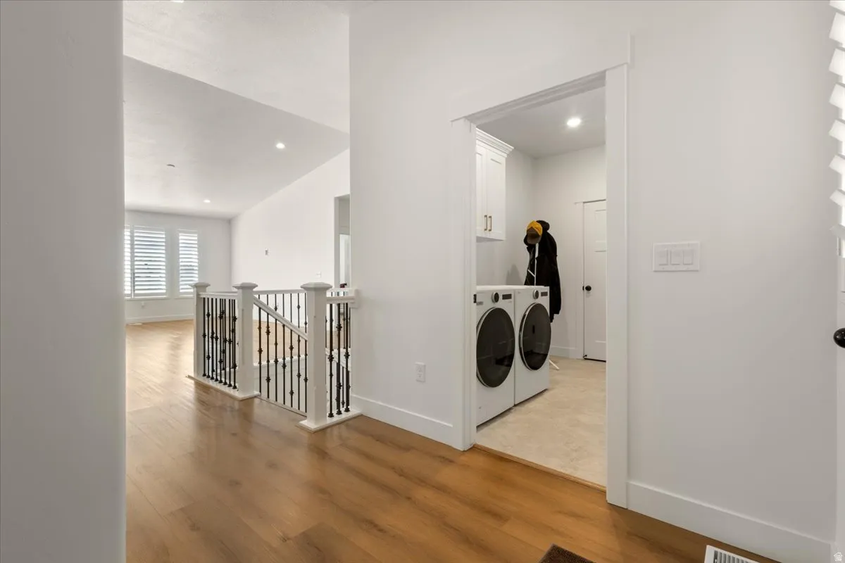 Dedicated laundry area with white cabinetry, gold-tone hardware, and recessed lighting