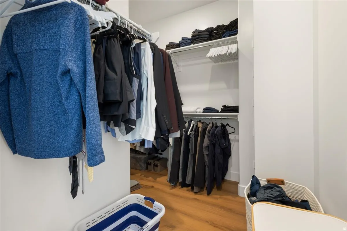 Walk-in closet with multiple hanging rods, wire shelving, wood-finish flooring, and white walls